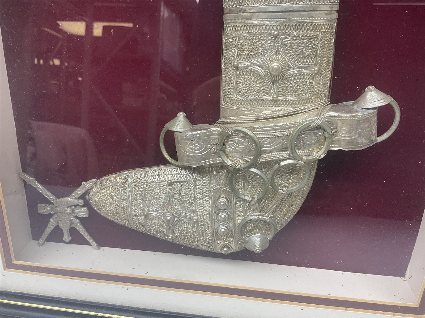 20th century silver Khanjar dagger from Oman, heavily decorated with filigree throughout, dome shaped pommel and waisted grip, the sheath with fastening rings, with miniature curved dagger accessory, housed in red lined glazed box frame, L38cm