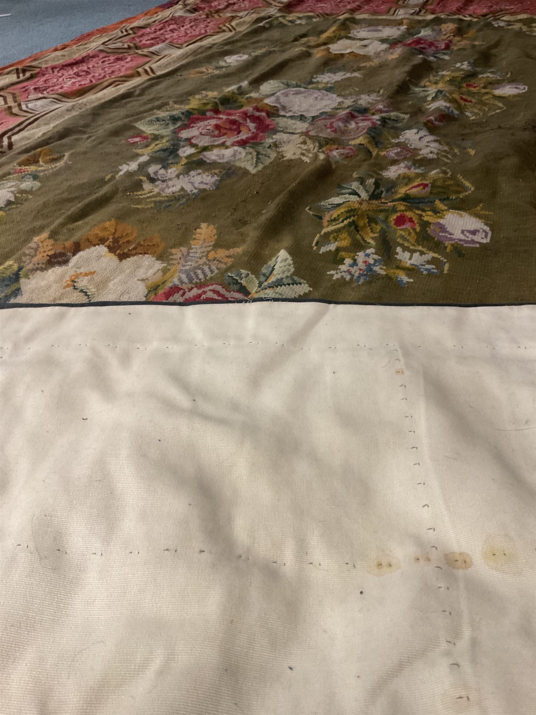 Needlework rug, green ground field decorated with flowers, the border decorated with a series of geometric panels with scroll and anthemion decoration, Greek key outer border 