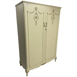 French classic design cream painted double wardrobe, the doors decorated with gilt and cream applied urn motifs with extending bell-flower festoons and ribbon twists, enclosing shelf and hanging rail, shaped apron on acanthus cabriole feet
