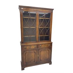George III design mahogany bookcase on cabinet, projecting dentilled cornice over two astragal glazed doors, lower section fitted with two drawers with lion mask handles over double cupboard, on plinth base