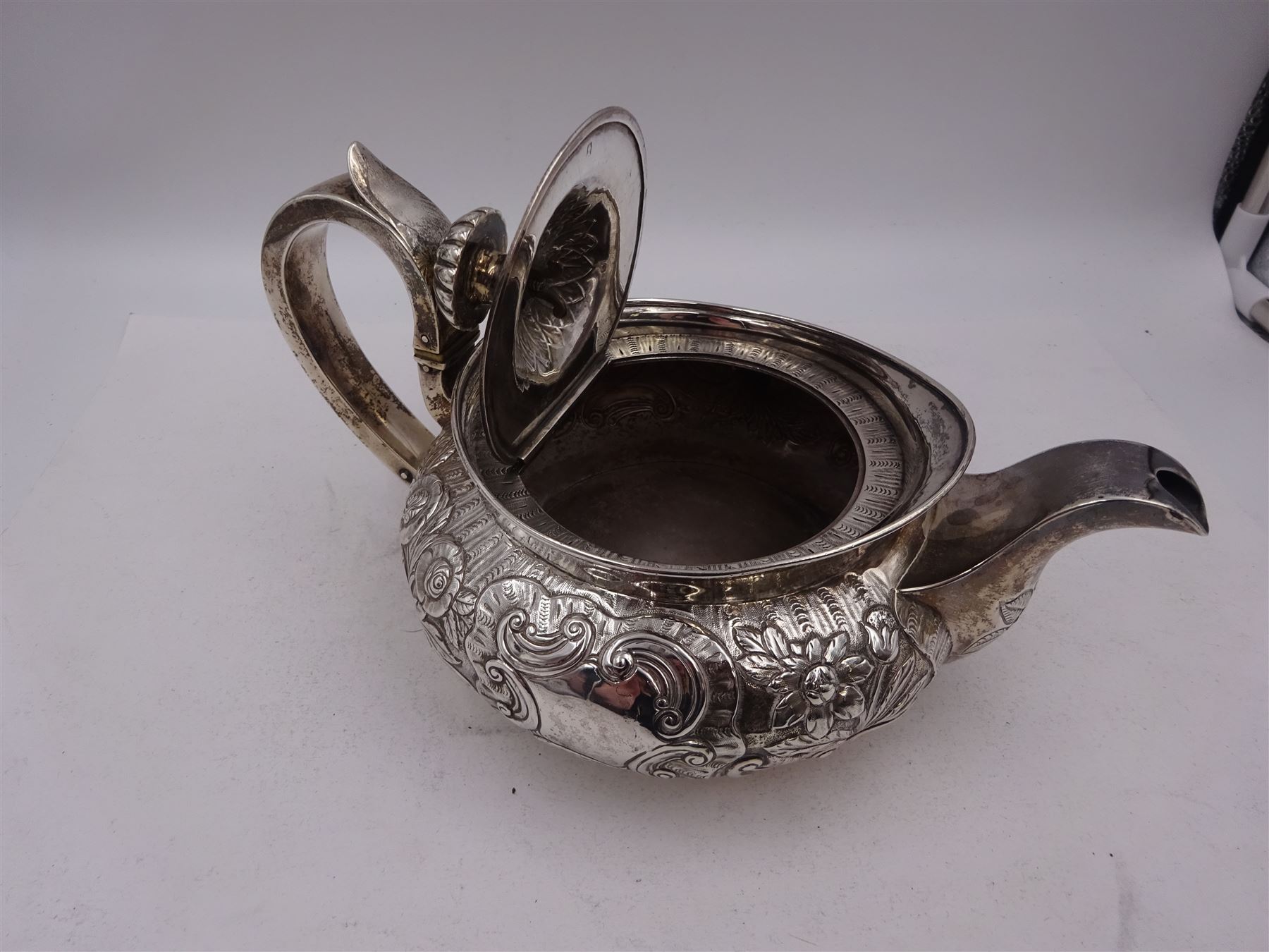 George III Irish silver teapot, of squat circular form, the body with repousse and chased floral and C scroll decoration, with capped C handle and ivory insulators, engraved to base 'Presented to Troop Sergeant Major John Percival, of the 4th Dragoon Guards by Alex D. Tait, Esq, late Captain in that corps as a mark of approbation of his steady and upright conduct when Sergeant Major of his Troop, Dublin, June 2nd 1843', hallmarked William Law, Dublin 1817, H12.5cm, This item has been registered for sale under Section 10 of the APHA Ivory Act