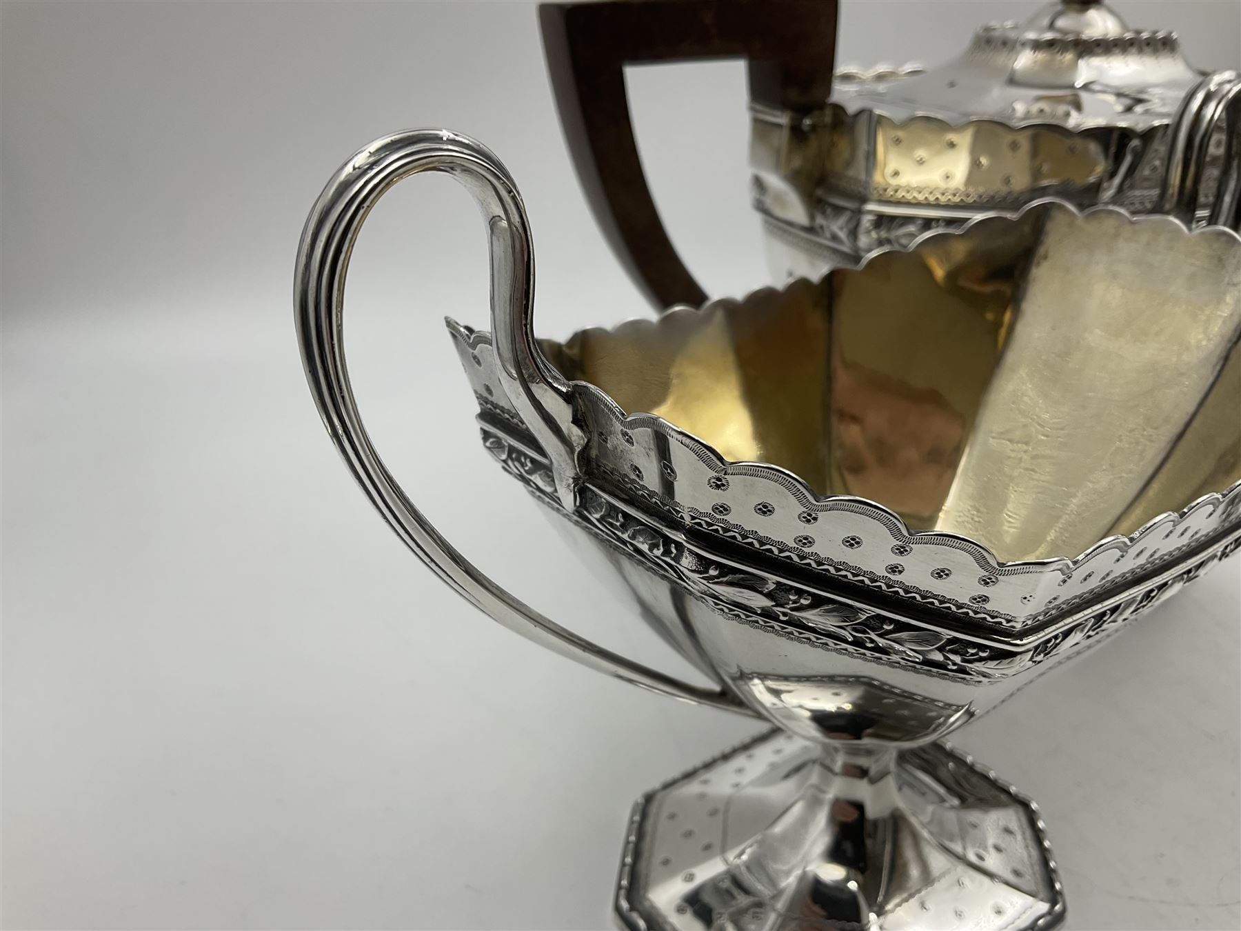 Victorian silver four piece tea service, comprising teapot, teapot stand, twin handled open sucrier and milk jug, each of octagonal form with foliate bud border and engraved decoration including crest to canted panels, and vacant panels, the teapot with ivory finial to the hinged cover and later wooden handle, hallmarked Edward Barnard & Sons Ltd, London1896, teapot including finial H15cm, milk jug including handle H16cm, teapot stand W11.5cm

This item has been registered for sale under Section 10 of the APHA Ivory Act