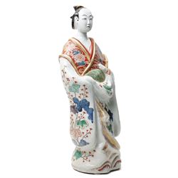 Large Japanese Imari porcelain figure, modelled as a Bijin, wearing a long kimono decorated with apple blossom and leafy branches on a white ground, with gilt detailing, possibly Edo period, H63cm