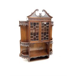 Mahogany wall hanging cabinet with carved detail, two glazed doors, above two shelves 