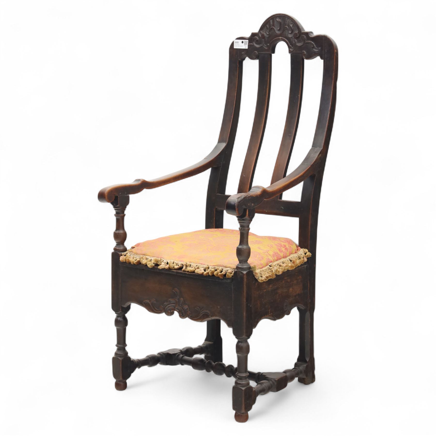 18th century oak provincial armchair, arched and carved cresting rail above triple splat back, shaped arms on turned supports, stuff-over seat upholstered in damask fabric, carved front frieze on turned legs united by stretchers