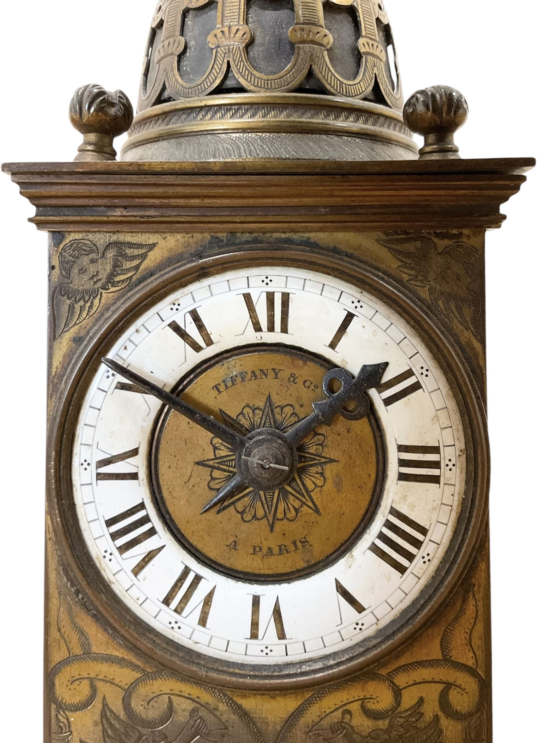 Tiffany- early 20th century brass cased 8-day mantle clock, rectangular case with engraved images taken from classical & mythological fables, with an open strapwork dome, finials to the corners and a cast figure of a standing maiden, case raised on a splayed base with acanthus engraving, enamel dial with Roman numerals, minute markers and steel hands, dial centre engraved Tiffany & Co Paris, twin train French movement with a platform escapement wound from the rear, baseplate of case stamped with the serial numbers 4372 & 5652. With key. 
Provenance from Chatsworth House, Derbyshire.