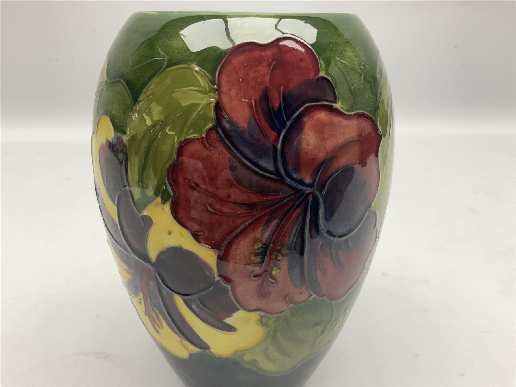Moorcroft Hibiscus pattern vase of ovoid form, decorated with pink, yellow and purple flowers on merging blue and green vase, with impressed and painted marks beneath, H18cm