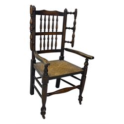 Early 19th century ash armchair, the back with winged spindles extending from a shaped top rail, above a splat of two rows of vertical spindles, with curved arms and a rush seat, raised on turned supports united by double stretchers terminating in castors