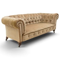 Victorian mahogany framed two seater Chesterfield settee, traditional shape with rolled back and arms over sprung seat, upholstered in buttoned-back neutral fabric, raised on turned front supports with ceramic castors