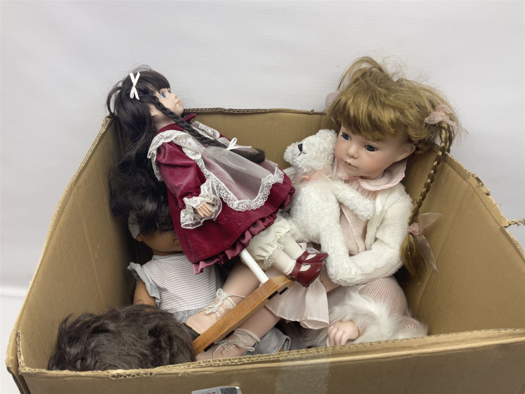 Two decorative wicker dolls prams, one with lace parasol,  and eleven dolls, including Leonardo Collection porcelain dolls, tallest pram including parasol H105cm