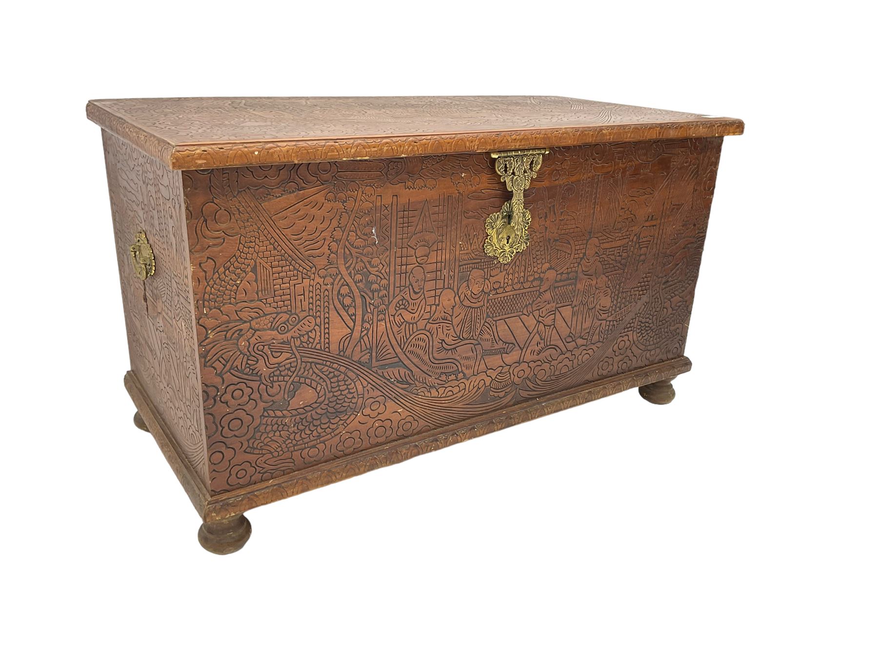 Hong Kong camphor wood chest, rectangular hinged top, carved all over with traditional scenes and dragon boats, on bun feet