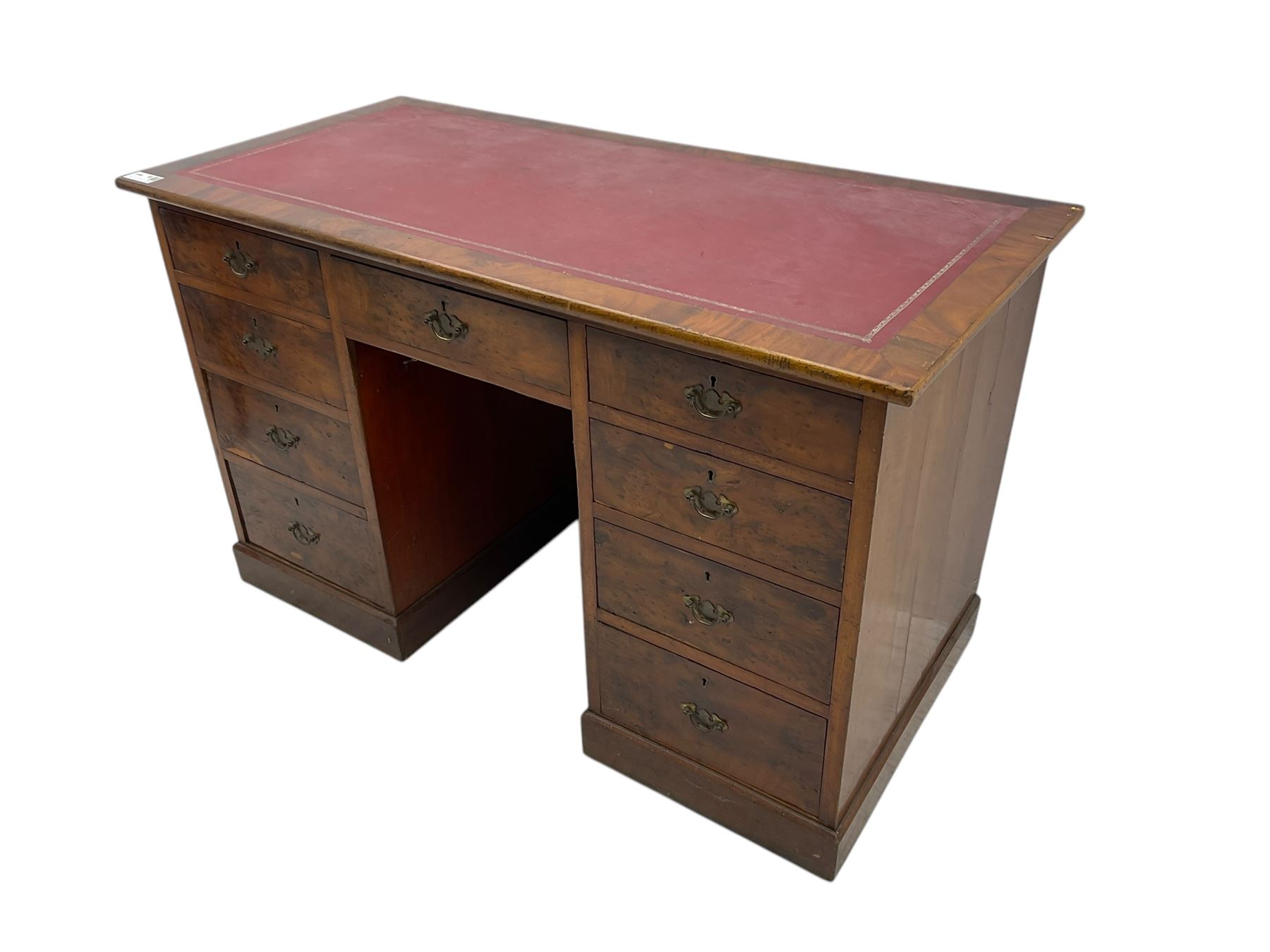 Late 19th to early 20th century walnut pedestal desk, rectangular top inset with red tooled leather writing surface, over a central frieze drawer flanked by two pedestals, each fitted with four graduated drawers with brass escutcheons and drop handles, the whole raised on a plinth base