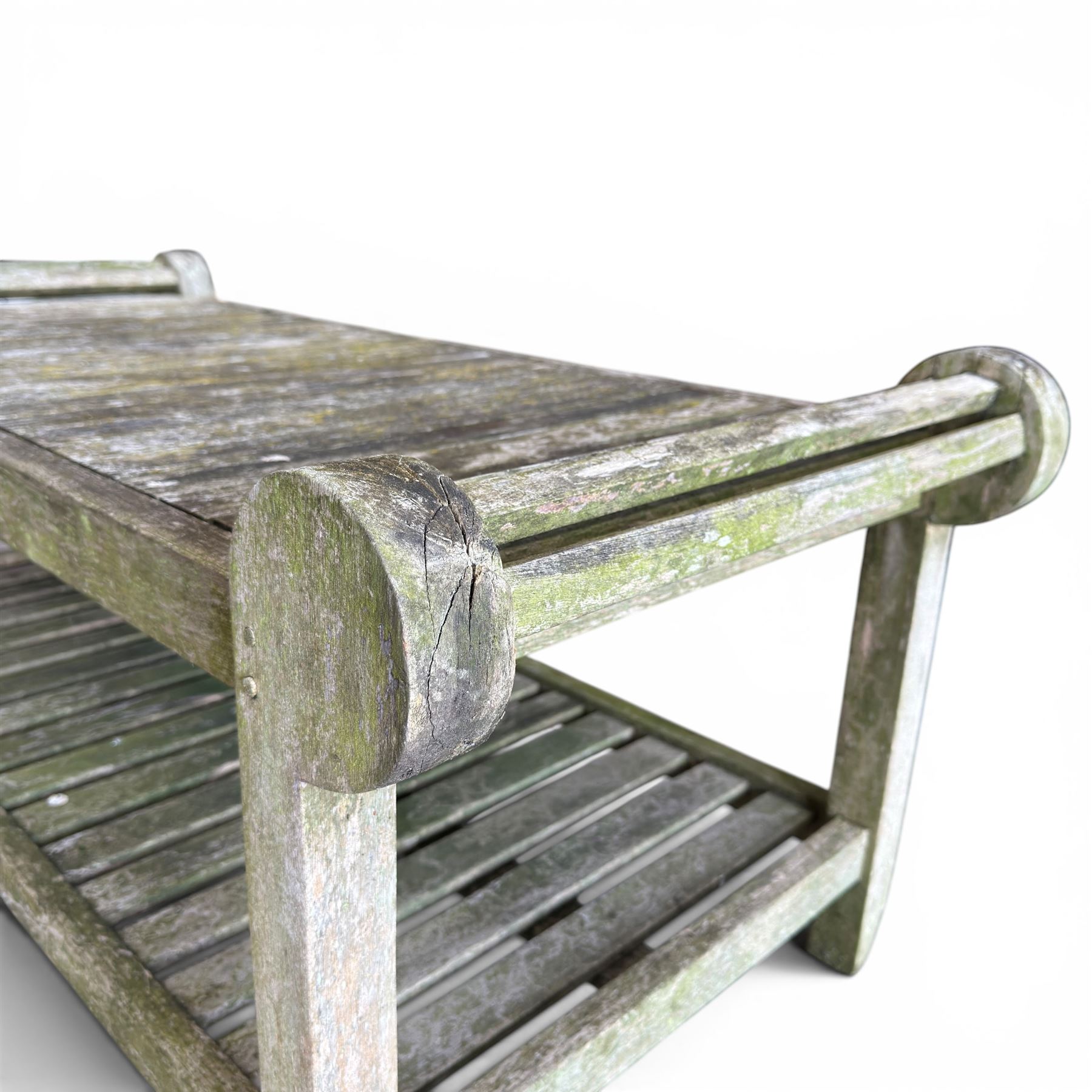 Lutyens design weathered teak garden bench with matching two-tier table, the bench with shaped arched and slatted back over rolled arms and slatted seat