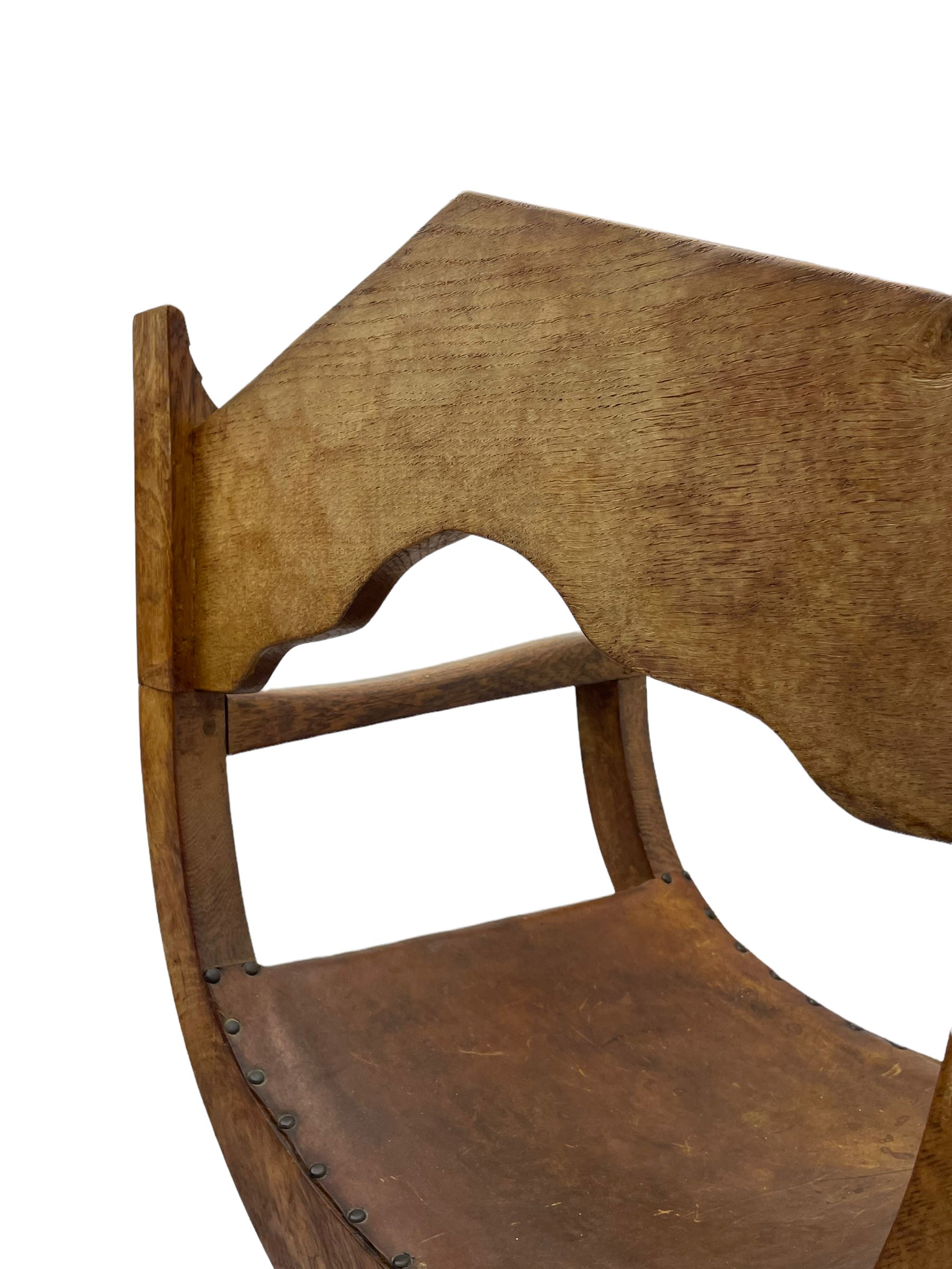 'Gnomeman' oak curved x-framed throne chair, sloped arched cresting rail carved with arcade, studded slung leather seat, the supports joined by sledge feet, rear upright carved with gnome signature, by Thomas Whittaker of Littlebeck