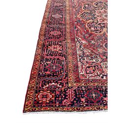Antique Persian coral ground carpet, the large central floral pole medallion with extending foliate designs, the thick guarded indigo border with repeating flower heads and circles