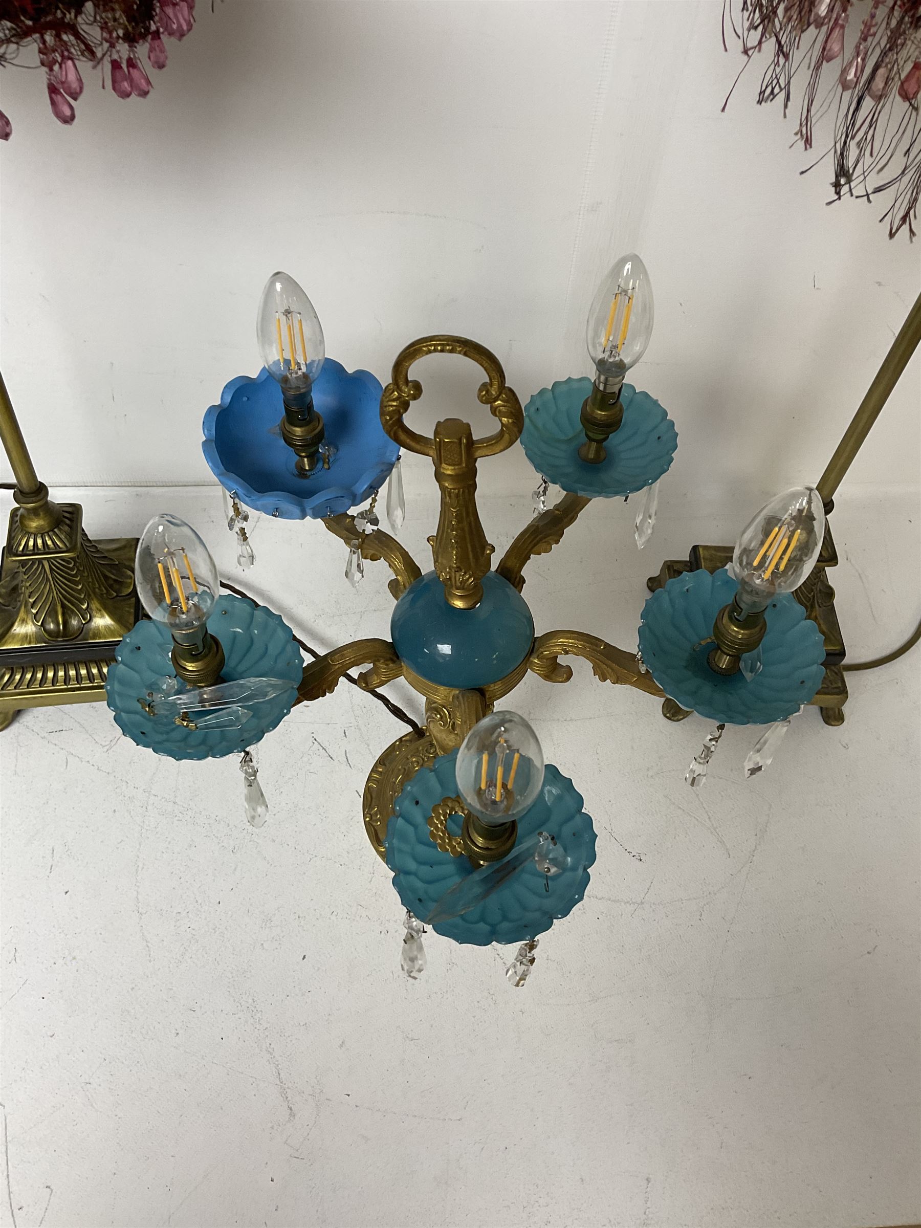 Brass table lamp, modelled as a candelabra with five branches, each with blue glass candle holders with crystal drops, H47cm, together with a pair of cast metal table lamps with acanthus leaf detail, upon a stepped square base, with red fabric feather and tassel shades, H78cm