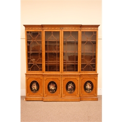 Sheraton Revival satinwood breakfront bookcase, frieze painted with scrolling leafage above four astragal doors with adjustable shelves, the base with four doors painted with floral sprays in oval panels, on a plinth base, W234cm, H235cm, D52cm