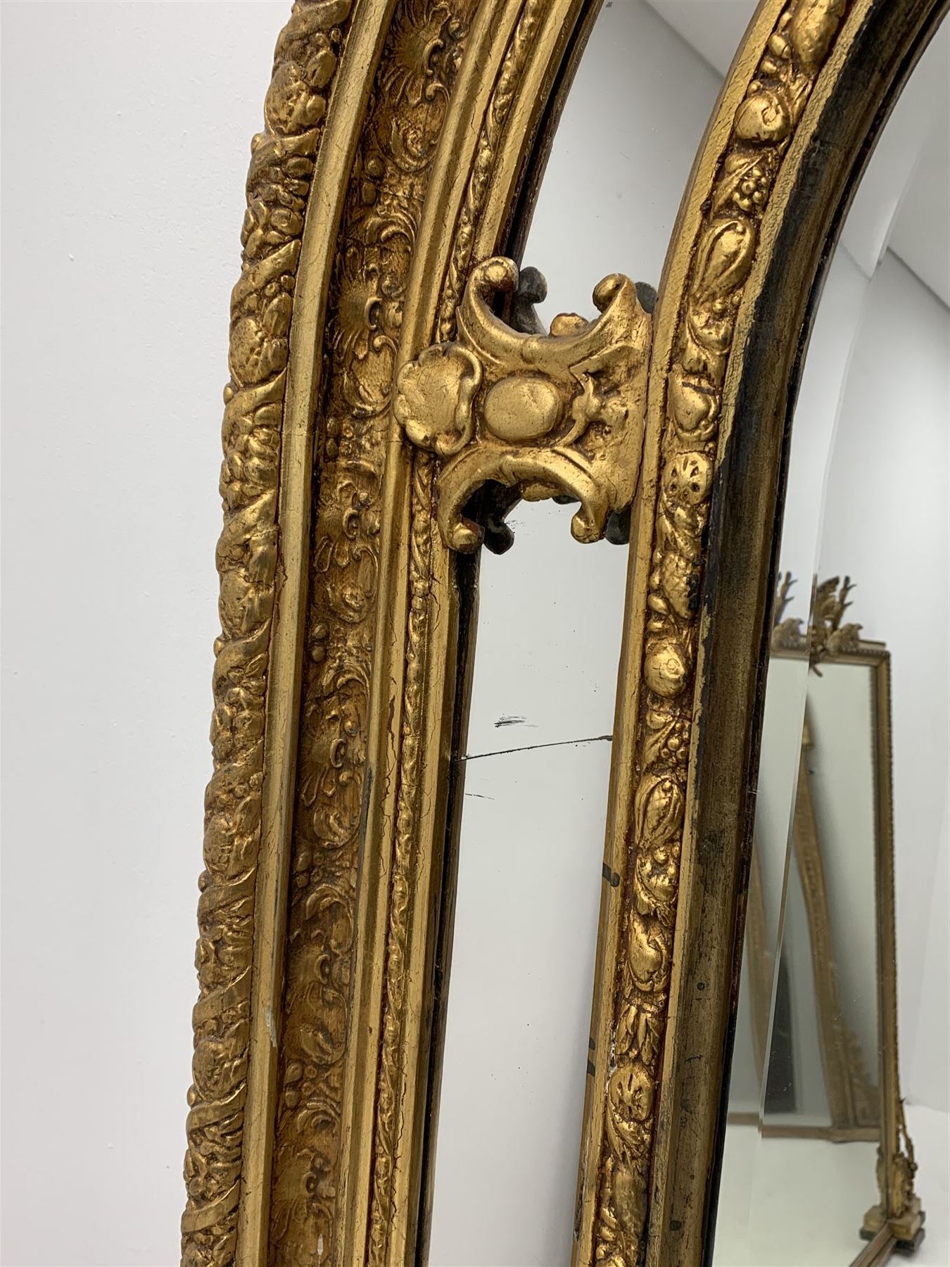 Gilt Rococo style mirror, arched top with central cartouche and oak leaf moulded pediment, floral and fruit moulded surround with segmented glass panels, bevelled central pane, c-scroll shell and acanthus leaf brackets