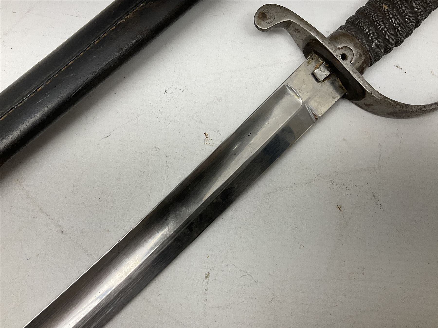 Mid-19th century Custom’s officer/Constabulary sidearm, with plain 60.5cm slightly curving fullered blade double edged at tip,  steel knucklebow and downswept quillon, stepped pommel and ribbed fishskin grip; in leather covered scabbard with steel locket, frog stud and chape L76cm overall