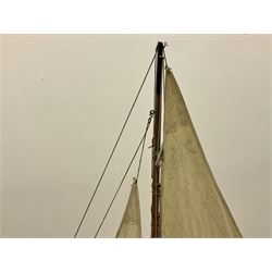 Early 20th century large pond yacht with mahogany hull, stained pine keel with brass rudder, simulated deck hatches and brass fittings, rigged as a staysail schooner (?) with four sails L117cm H148cm; loose mounted on stained pine stand