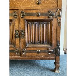Shapland and Petter - Arts & Crafts period oak dresser, raised gallery top with spade balustrade, central bevelled mirror flanked by two cabinet, astragal glazed doors with yellow tinted glass and bullseye panes, the sides with pierced heart shaped decoration, fitted with two drawers and two double cupboards, enclosed by linenfold panelled doors,  copper work strap hinges and fixtures, on shaped spade feet, the locks stamped 'S&P'