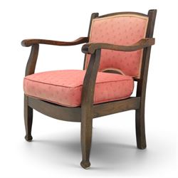 Early 20th century small oak open armchair, arched upholstered back with brass stud border over shaped seat cushion upholstered in pink foliate fabric, shaped open arms on square supports