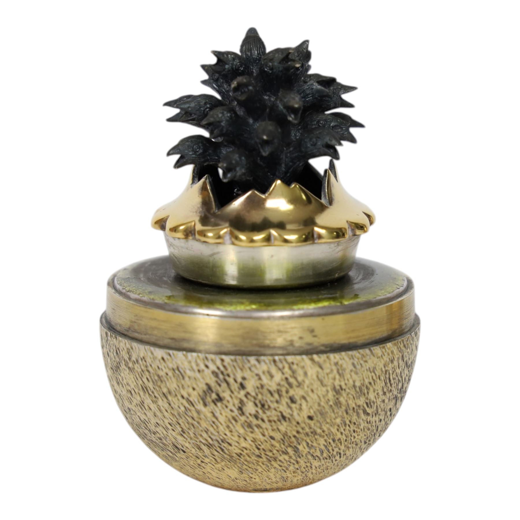 Late 20th century silver and silver-gilt surprise egg, the textured gilt exterior opening to reveal a clutch of chicks, the clustered heads supported upon a spring, within a jagged and lobed silver and gilt encasement, with green enamel surround, hallmarked Stuart Devlin, London 1982, H7cm