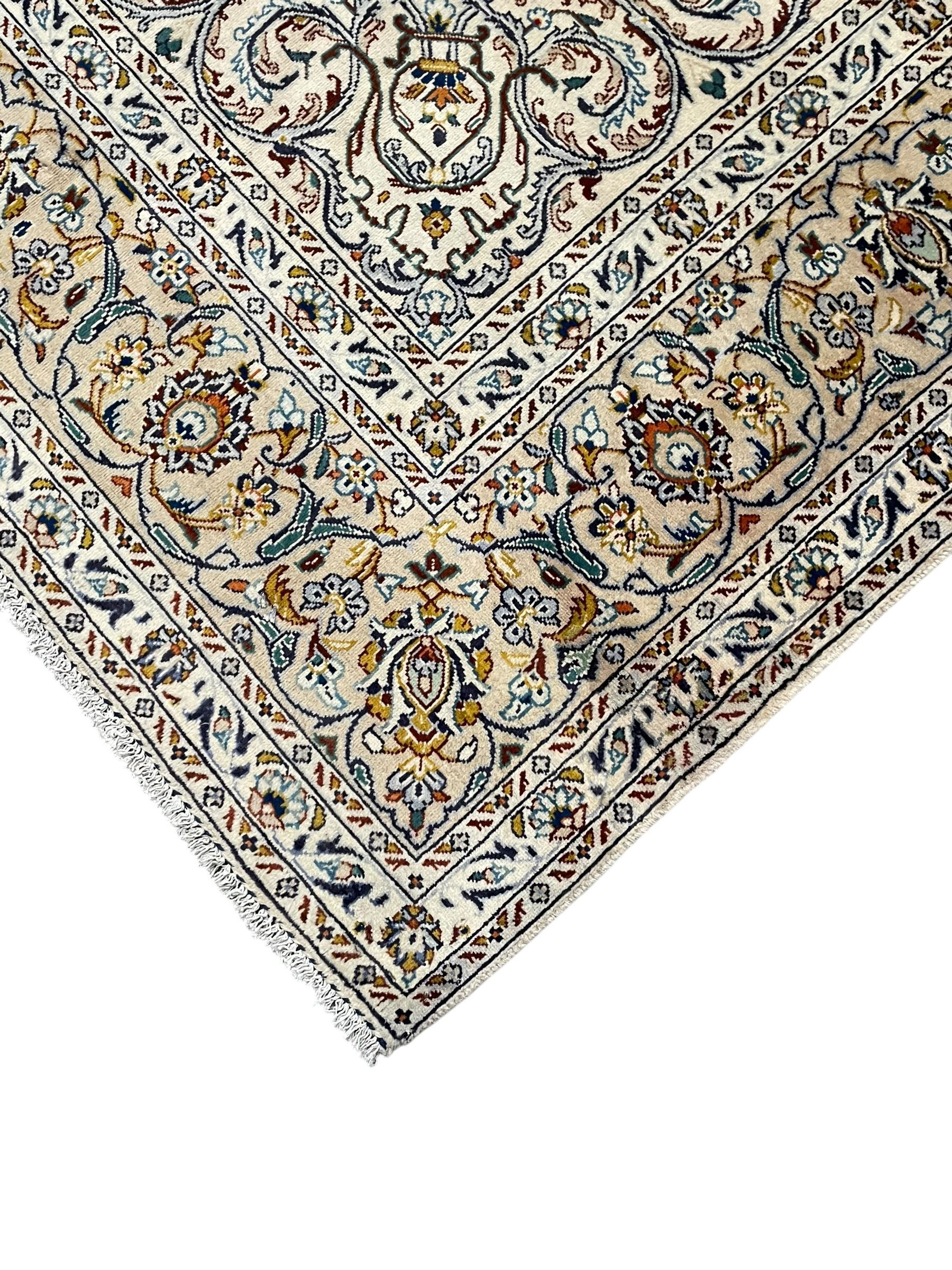 Persian Kashan ivory ground carpet, central pole medallion surrounded by swirling leafy branches and stylised plant motifs, scrolled foliate spandrels, the main border decorated with scrolling pattern and repeating palmettes, within floral patter guard stripes 
