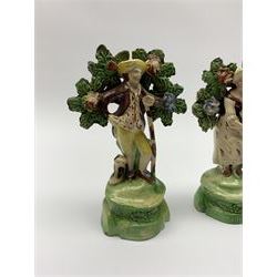 Pair of 19th century Staffordshire figures, modelled as 'Sheperd' and 'Sheperdess', each stood before bocage and accompanied by dog, upon titled bases, largest H14cm, together with a further similar example, the base inscribed 'Sheperd' 