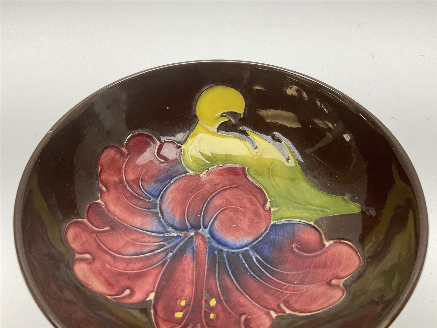 Small Moorcroft pin dish, decorated in the Hibiscus pattern with brown ground, D11cm