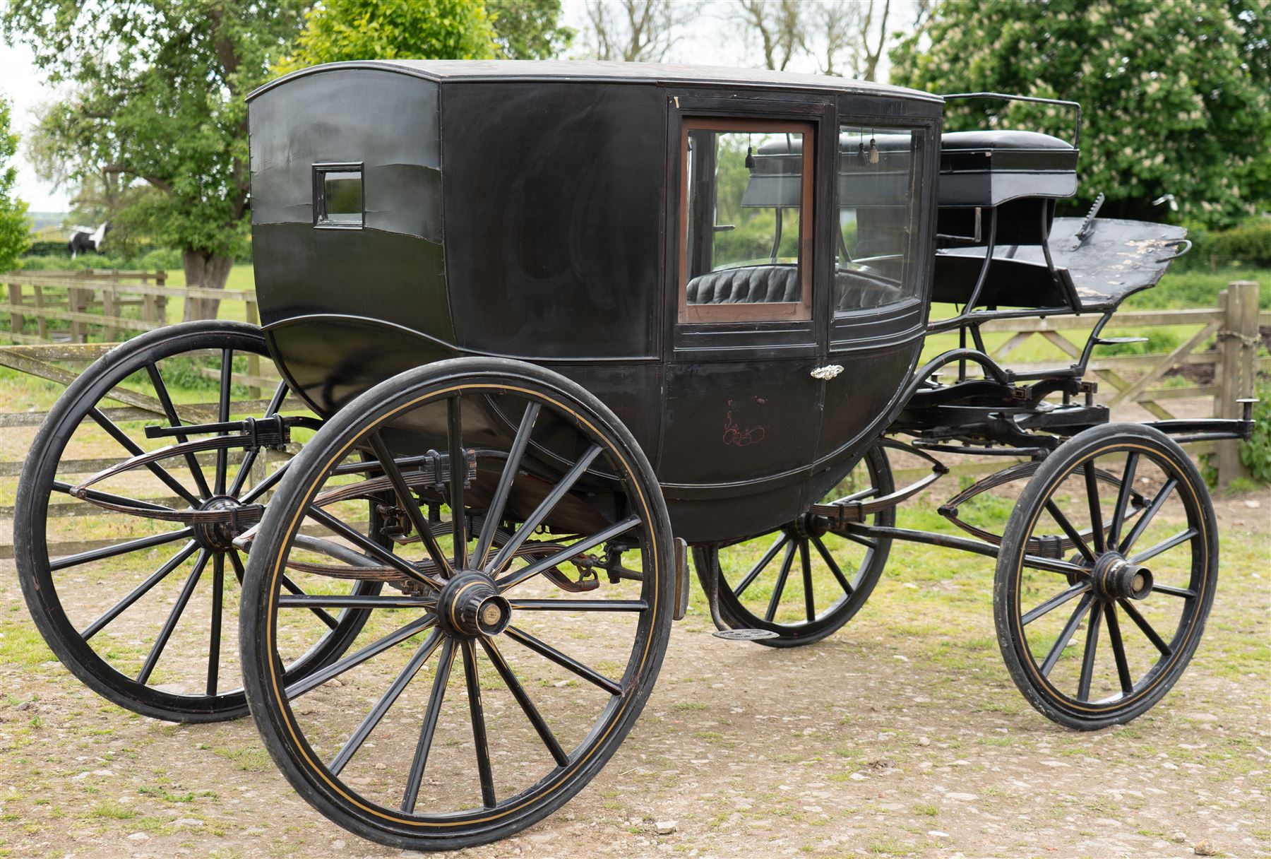 Town Coach by John Marstons Birmingham - Ex Film

A black painted five glass Town Coach by John Marston's Carriage Works Ltd, Birmingham, with enclosed glazed passenger compartment, curved front glass, external coachman's box seat and pole for driving with a pair of horses. The carriage has a timber coach body with buttoned black leather interior, blue upholstered seat cushions, plated exterior door handle, maker plates to the body and step, and John Marston marked hub caps. Mounted on black painted wooden spoked wheels with rubber tyres, leaf spring suspension, underbody turntable steering and iron fittings throughout.
Featured on the film set of 'Victoria' with Jenna Coleman

Features

• Black painted enclosed coach body
• Glazed passenger compartment with five windows
• Curved front glass
• Buttoned black leather interior
• Blue upholstered seat cushions
• External coachman's box seat
• Timber coach body
• Wooden spoked wheels
• Rubber tyres
• Leaf spring suspension
• Underbody turntable steering
• Pole for pair of horses
• Iron foot steps
• Plated exterior door handle
• Maker plates for John Marston's Carriage Works Ltd, Birmingham
• John Marston marked hub caps
• Featured on the film set of Victoria with Jenna Coleman

Dimensions:
Overall length: 390 cm
Width: 190 cm
Height: 214 cm

Wheel Diameters:
Front wheels: 104 cm
Rear wheels: 134 cm

Seating:
Coachman's box: 2
Passenger compartment: 4