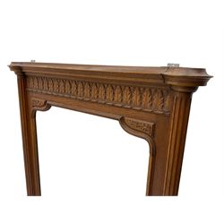 Early 20th century French oak overmantle mirror, projecting cornice with broken foliate carved frieze, shaped rectangular bevelled plate flanked by fluted column uprights