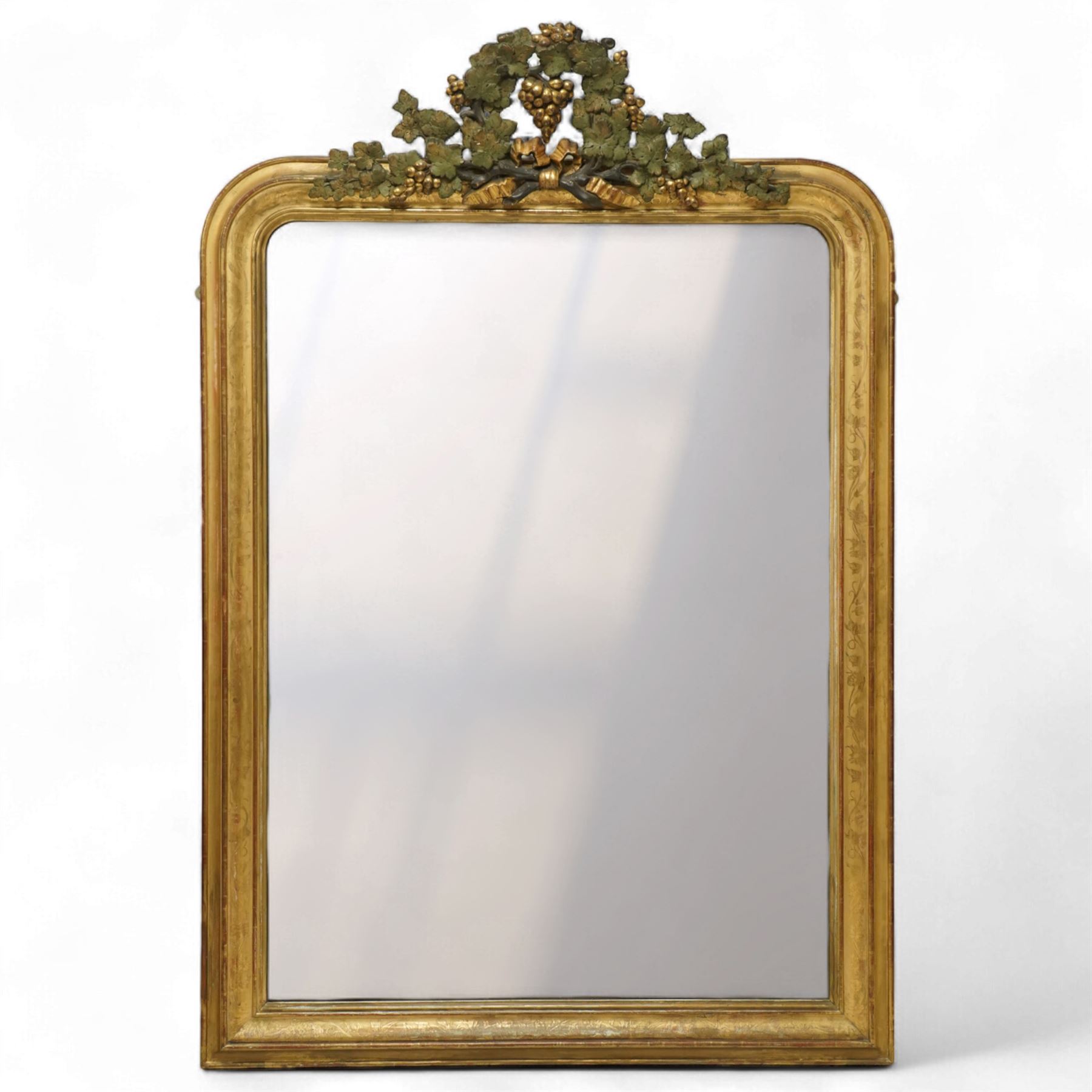 Louis XVI style gilt overmantel mirror, arched rectangular form with moulded frame, surmounted by a pediment carved with ribbon-tied grapevine and leaf decoration, enclosing a plain mirror plate, circa 1900