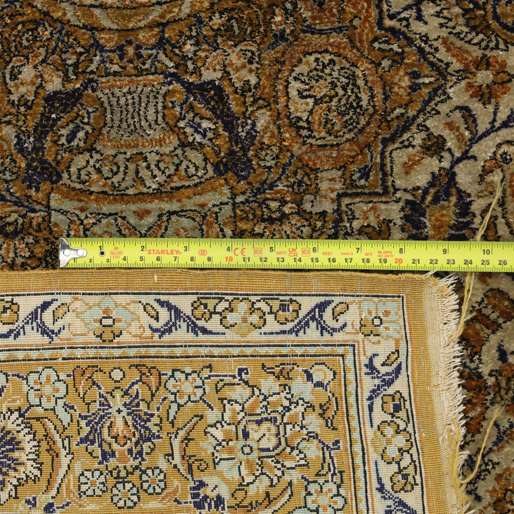 Persian Kashan design silk and wool blended rug, with a central medallion incorporating vases and scrolling floral motifs, set against a dark blue and ivory ground within a patterned border, some fraying to end fringes