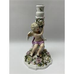 A late 19th century Sitzendorf figural candlestick, modelled as a putto supporting a socket with swan head terminal, the spreading base heavily encrusted with flowers, with printed mark beneath, H32cm.