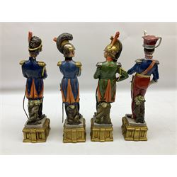 Group of seven Capodimonte figures of soldiers, to include four Bruno-Merli examples including Officer of the 12th Lancers 1820 and Captain of the 18th Hussars 1815, both raised upon ornate gilt plinths bearing British monarch motto in Latin 'Dieu et mon droit', and three further similar, all with crowned N mark beneath, tallest H32cm