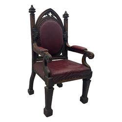 Late Victorian Gothic-revival armchair, arched crest rail carved with tracery and trefoil detail, padded circular back and seat, brass studded burgundy leather upholstery, shaped armrests with scrolled terminals, on square tapering supports