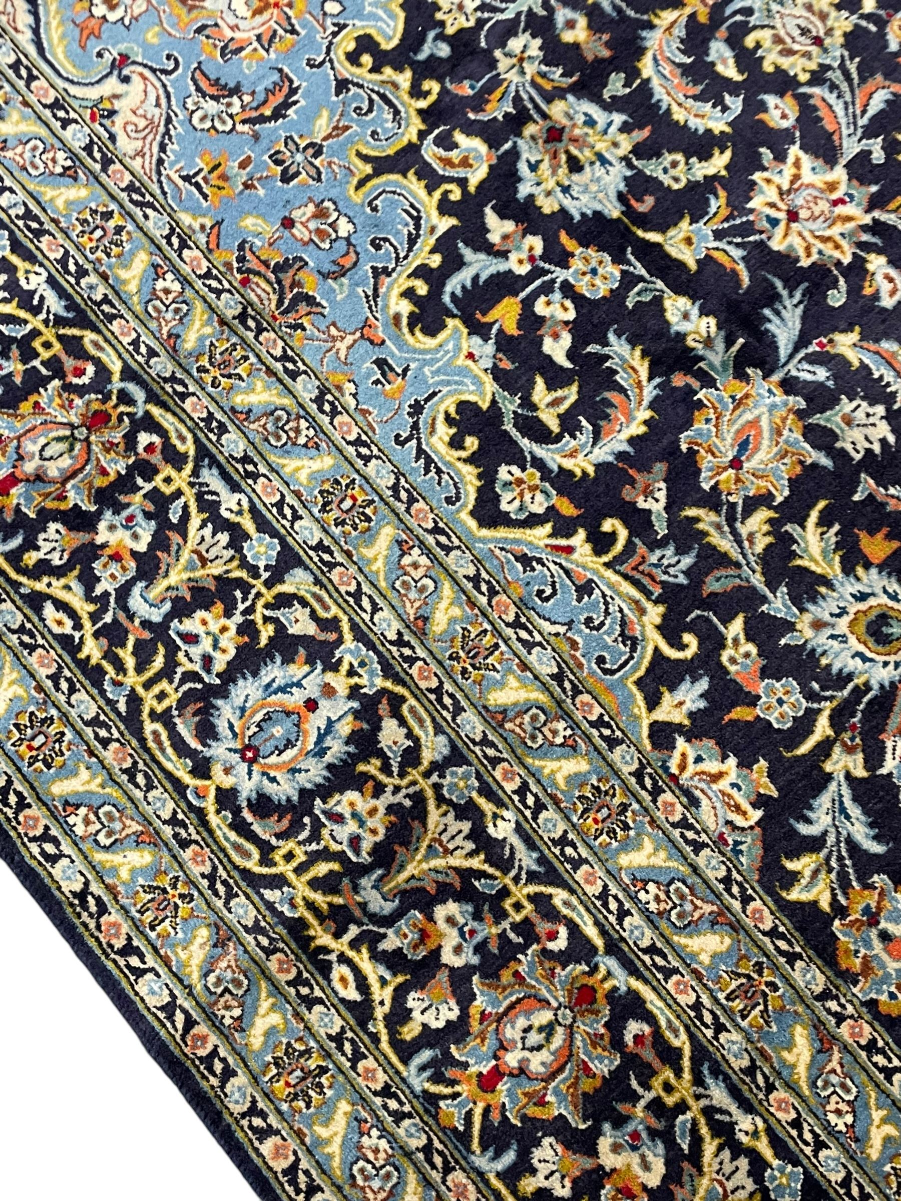 Persian Kashan indigo ground carpet, floral pattern light blue ground central medallion and spandrels, the fielding decorated with interlacing leafy branches and palmettes, the repeating floral pattern border enclosed within guard stripes