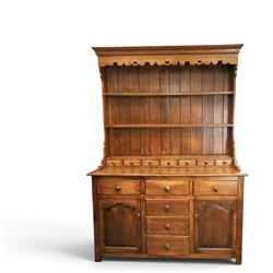 Traditional oak dresser with plate rack in the manner of Titchmarsh & Goodwin, plate rack with projecting cornice and shaped and pierced frieze, tongue and groove back three racks, over seven small spice drawers, the lower section with three short drawers, central bank three of drawers, fielded panelled sides and cupboard doors, raised on stile supports