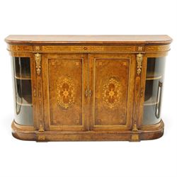 Large fine Victorian figured and burr walnut credenza, the breakfront D-shaped top with moulded edge, over an ornate frieze with inlaid Aesthetic Movement scrolling and geometric ornament, applied with gilt-metal ribbon-twist moulding and mounts, the central panelled doors profusely inlaid with scrolling foliate motifs and stringing, flanked by gilt-metal cartouche and scrolling acanthus corbel mounts, with flanking glazed bow-front side doors, on skirted base with further gilt metal foliate mounts