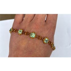 19th century gold emerald necklace, seven closed back octagonal cut and square cut emeralds, surrounded by a fancy bead setting, each spaced by a pierced scroll and bead design link, to a cable link chain necklace, with The Gem & Pearl Laboratory report