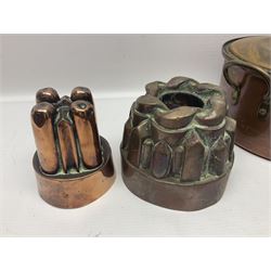 Four Victorian copper moulds, together with a graduating set of copper pans with wooden handles and finials to covers, largest pan 