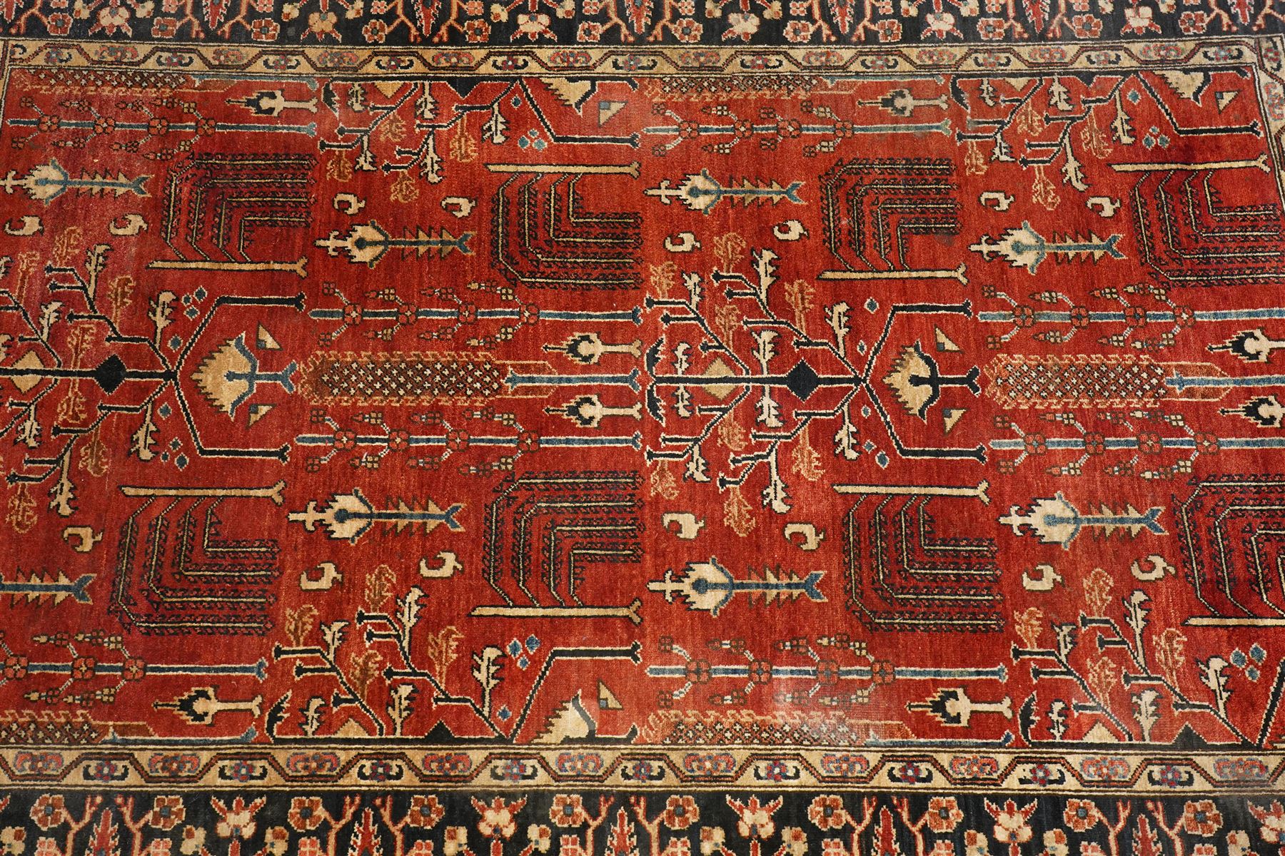 Anatolian crimson ground tribal rug, the field decorated with repeating geometric tree of life motifs with figural designs, the indigo guard band with stylised palmettes