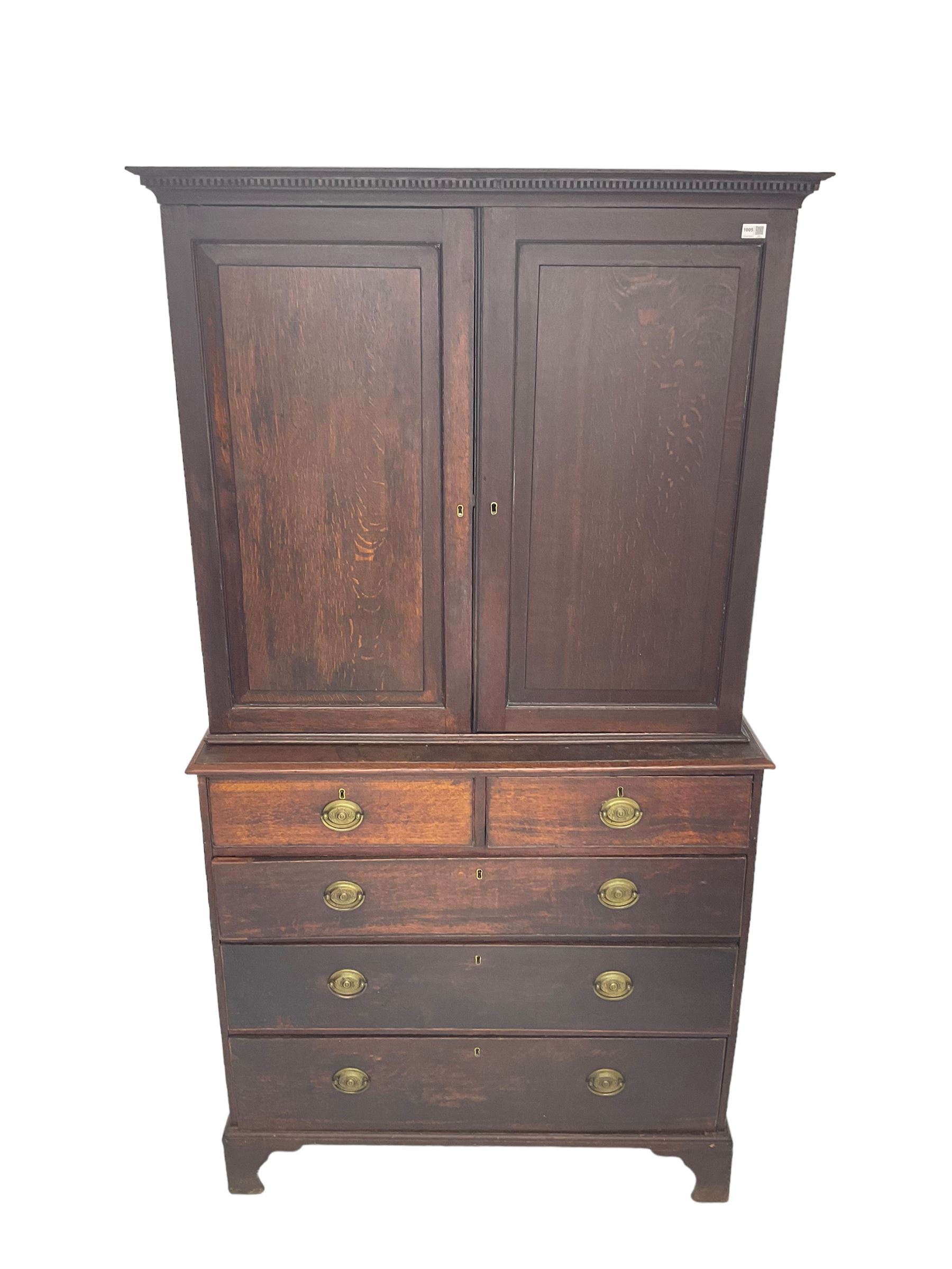 George III oak linen press, projecting cornice with dentil moulding over two panelled doors enclosing two adjustable shelves, fitted with two short over three long drawers, raised on bracket feet