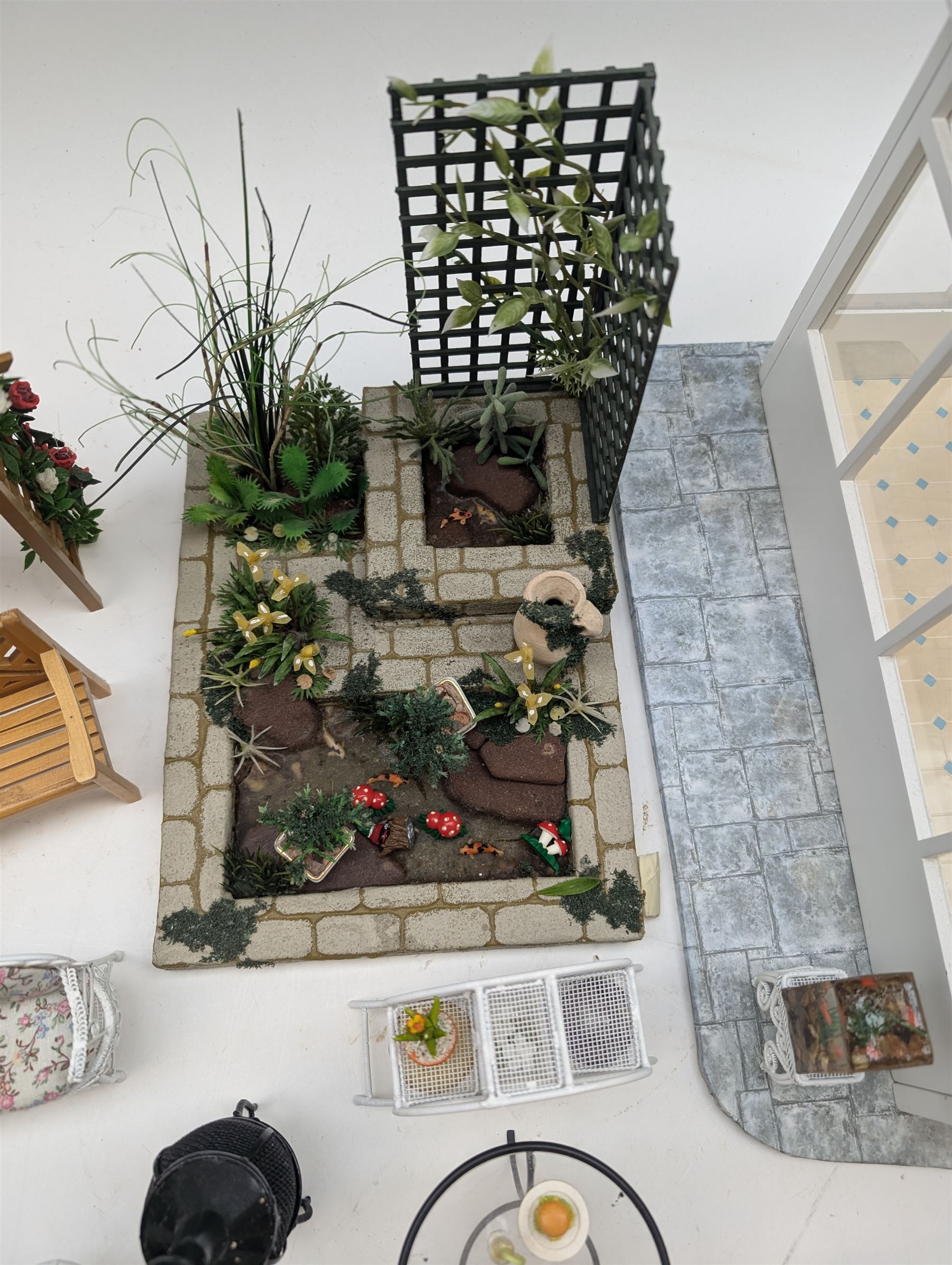 1:12 scale dolls house conservatory and garden accessories, including white wooden glazed conservatory on a stone effect base, black and white metal garden seating, barbecue, plant shelves, parasol, barbeque accessories, large planters, rabbit hutch, animals, chimenea, etc