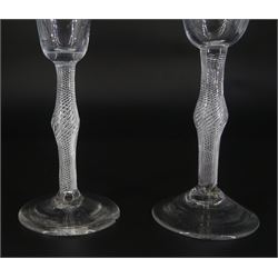 Two 18th century drinking glasses, with funnel and pan-top bowls, raised upon single series air twist knopped stem and conical feet, tallest H16cm