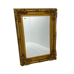 Gilt framed mirror, the frame decorated with cartouche and foliate corners with extending flower heads, inverted sea scrolls from the middle and egg and dart slip, bevelled plate