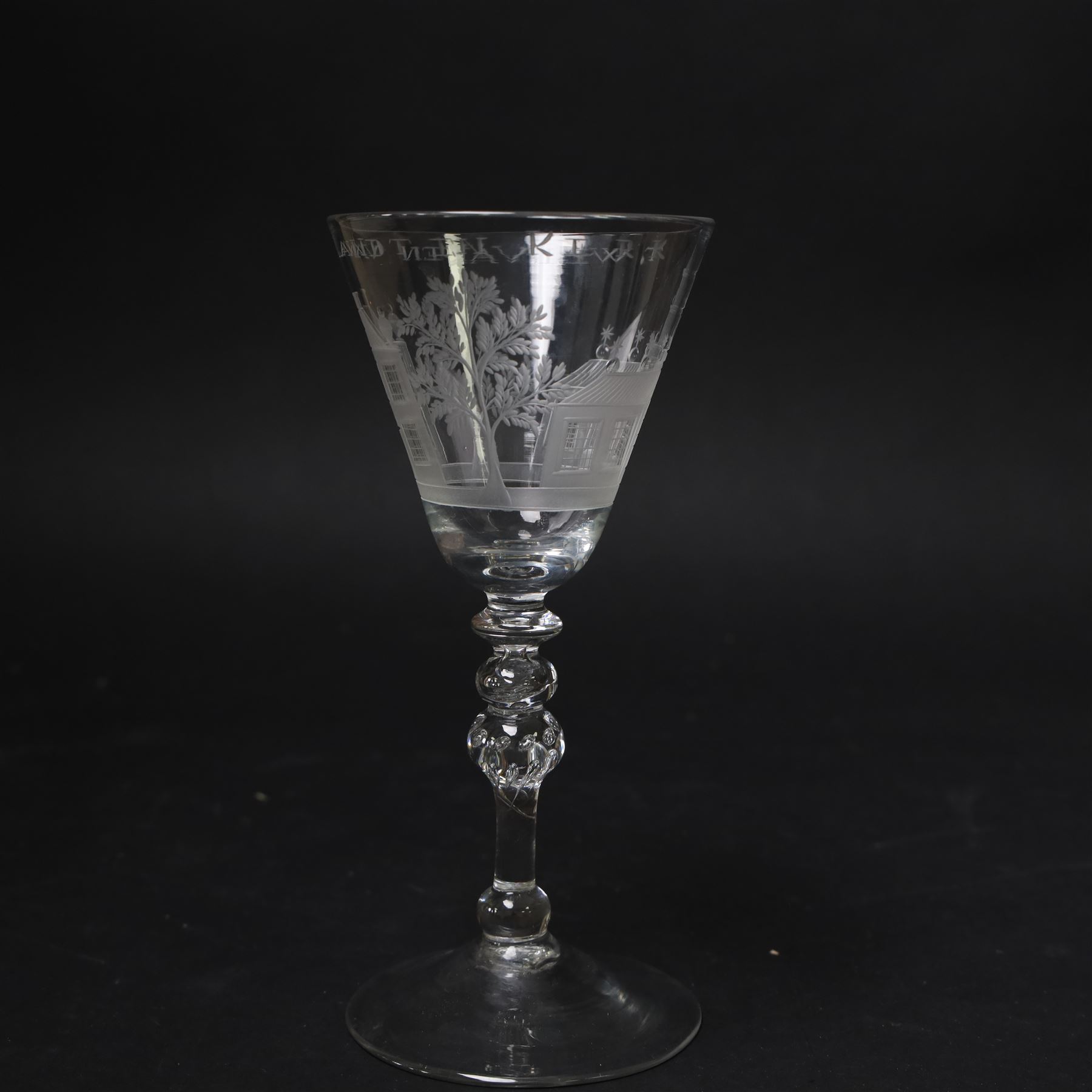 Dutch engraved Newcastle light baluster glass, circa 1760, the funnel bowl engraved with a two storey country house and church flanked by trees, beneath the inscription ‘T WELVAREN VAN LANDT ENKERK’ (The prosperity of the Country and Church), upon a multi knopped stem with beaded knop and basal knop, over conical foot, H18cm



