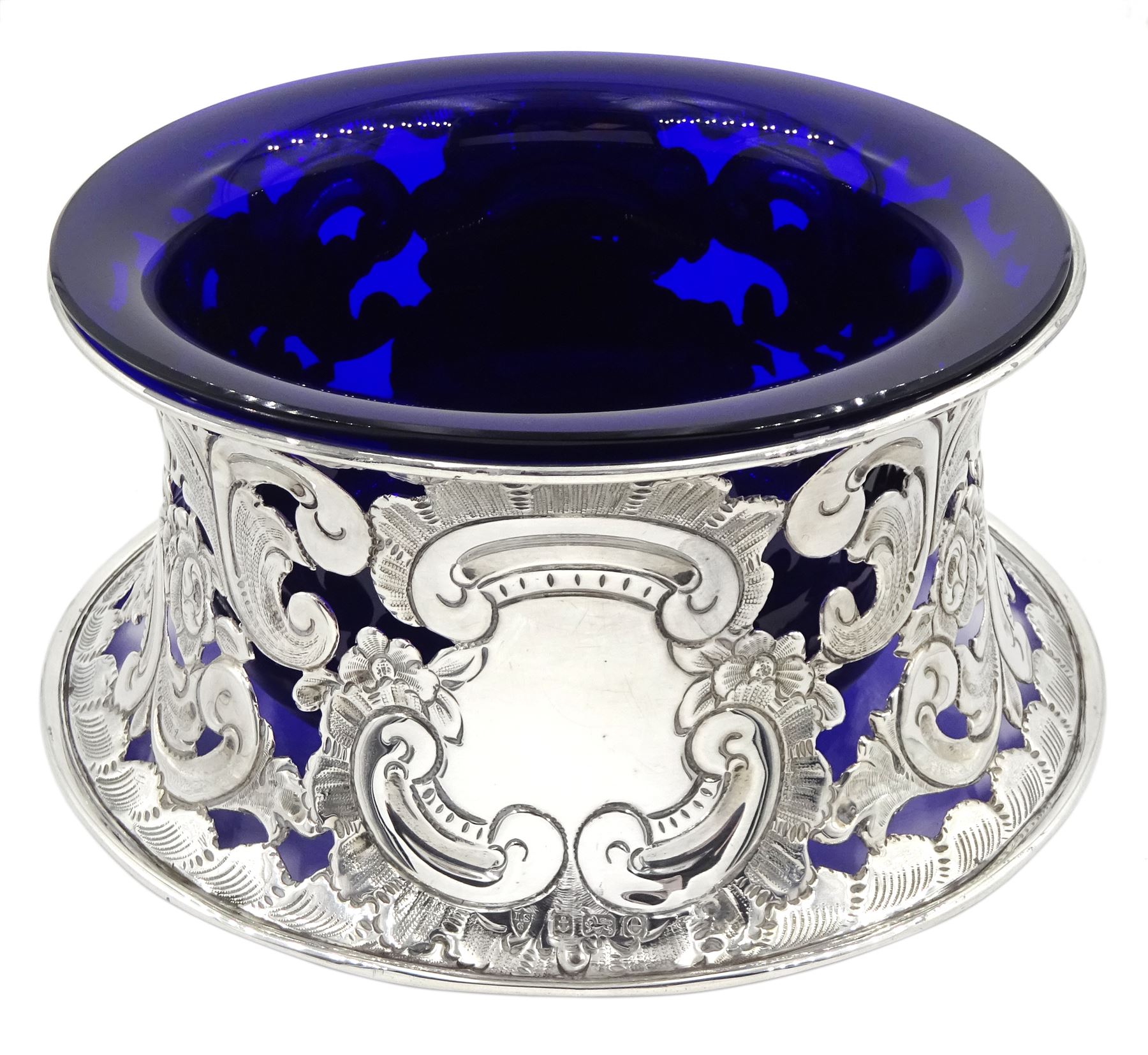 Edwardian silver dish ring in the Irish manner, of circular waisted form, embossed and pierced throughout with flower heads and foliate and C scrolls, hallmarked I S Greenberg & Co, Birmingham 1904, with accompanying blue glass liner, upper rim D17.5cm, approximate weight 6.84 ozt (213 grams)
