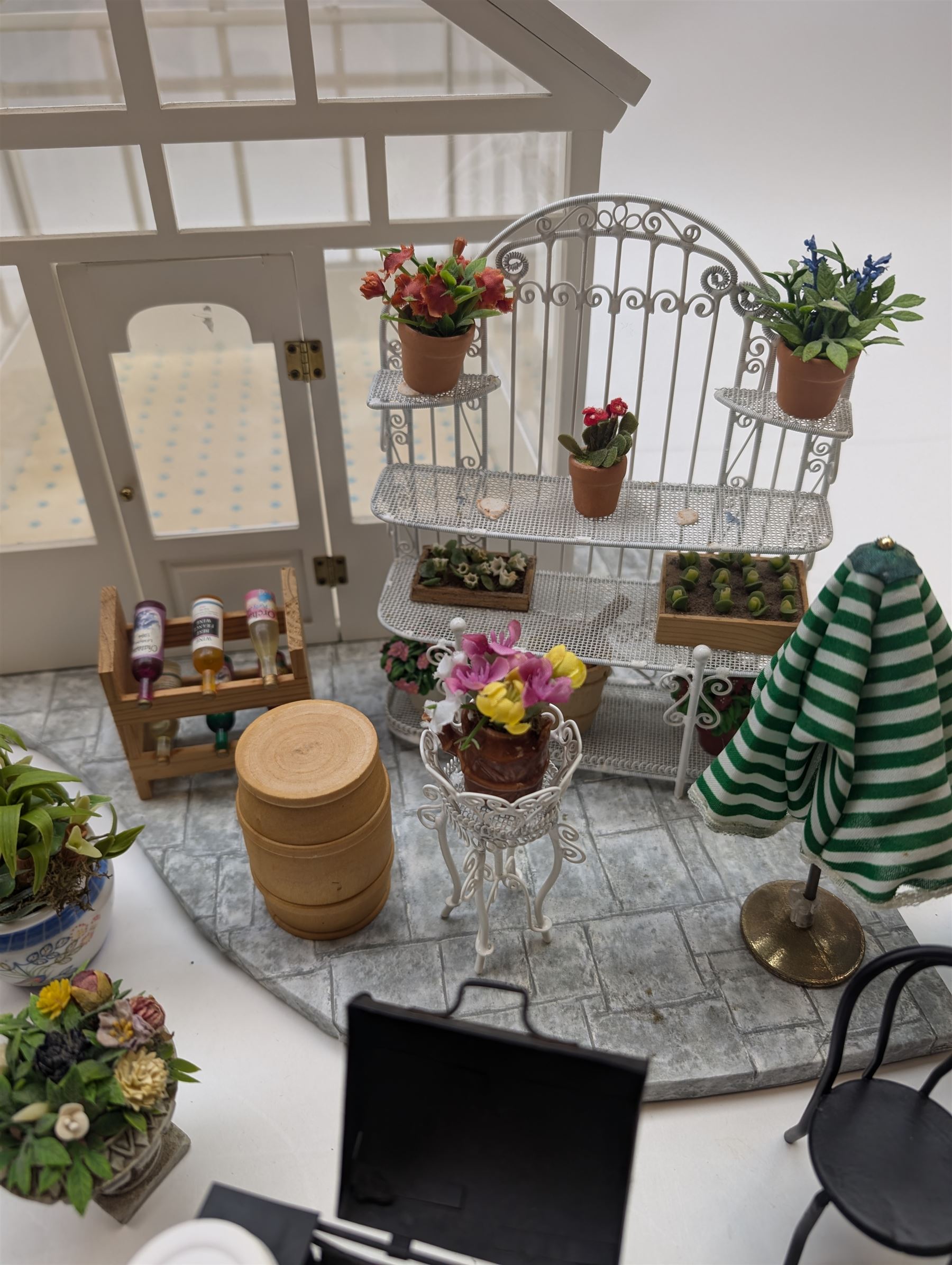 1:12 scale dolls house conservatory and garden accessories, including white wooden glazed conservatory on a stone effect base, black and white metal garden seating, barbecue, plant shelves, parasol, barbeque accessories, large planters, rabbit hutch, animals, chimenea, etc